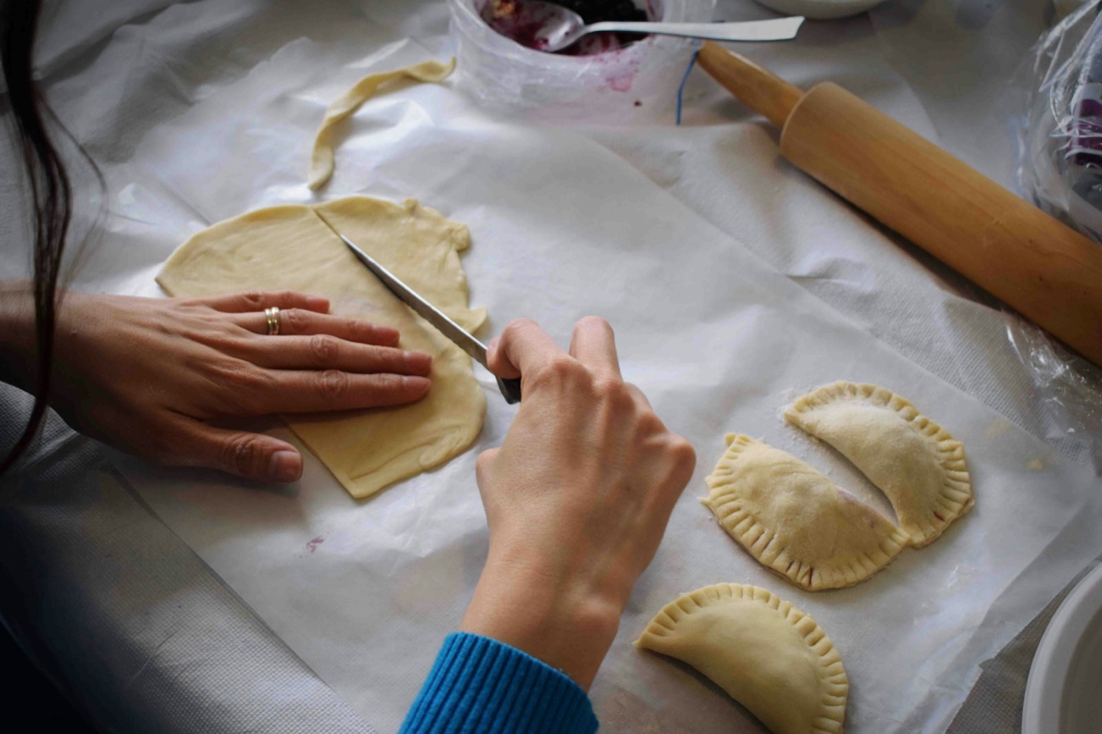 Manos armando empanadas sobre la mesa
